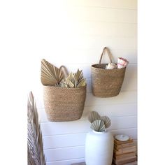 two baskets are hanging on the wall next to some books and other things in front of them