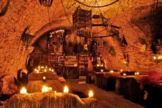 candles are lit in the middle of a room with stone walls and exposed ceilinging