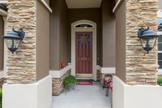 the front entrance to a home with two lamps on either side and a red door