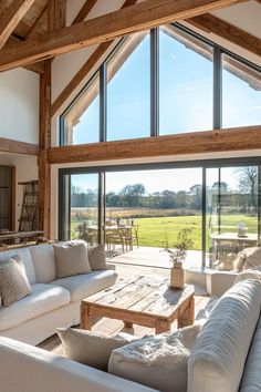 a living room filled with furniture next to a large open window covered in wood beams