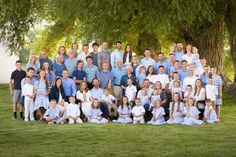 a large group of people are posing for a photo in front of a big tree