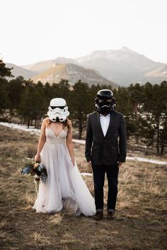 a bride and groom wearing storm trooper helmets on their wedding day at the mountain top