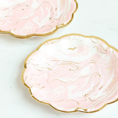 two pink plates sitting next to each other on a white counter top with gold trim