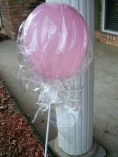 a pink lollipop sitting on top of a white pole next to a building