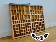 an old wooden box with many compartments on the bottom and inside, sitting on a hard wood floor