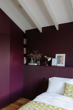 a bed sitting in a bedroom next to a purple wall