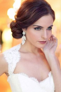 a woman in a wedding dress posing for the camera with her hand on her chin