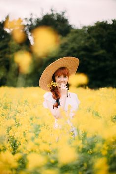 a woman with red hair wearing a straw hat and holding a flower in her hand