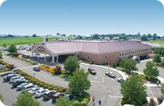 an aerial view of a parking lot with cars parked in front of it and a building on the other side