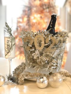 a bottle of champagne sitting on top of a table next to silver balls and tinsel