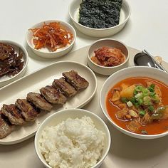 a table topped with bowls and plates filled with different types of food on top of it