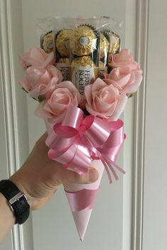 a hand holding a bouquet of pink roses in front of a door with chocolates