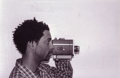 a man with dreadlocks is holding an old camera up to his face