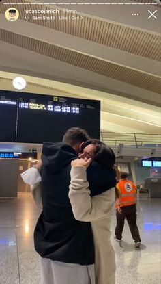 two people hugging each other in an airport