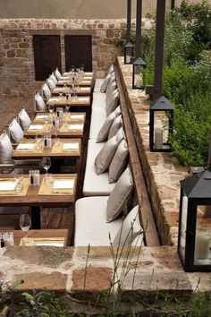 an outdoor dining area with tables, chairs and lanterns on the outside wall next to brick walls