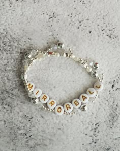 a white beaded bracelet with the word aurora spelled in small letters on top of it