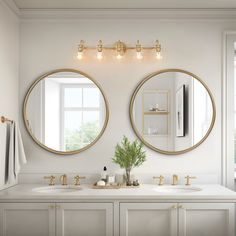 two round mirrors are above the sinks in this white bathroom with gold trim and brass fixtures