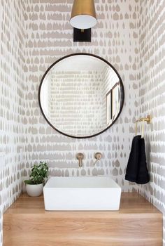 a bathroom sink with a mirror above it and a potted plant on the counter