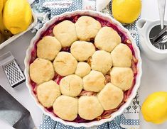 a pie that is sitting on a table next to some lemons and other food