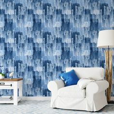 a living room with blue wallpaper and a white chair next to a lamp on a table