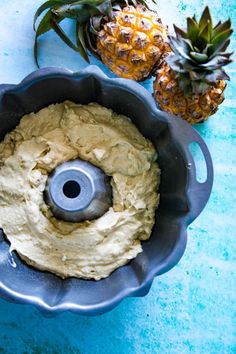 a pineapple is sitting next to a doughnut in a pan on a blue table