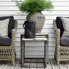 two wicker chairs sitting next to each other on a wooden floor near a potted plant