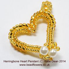 a heart shaped brooch with pearls attached to it