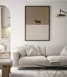 a living room filled with furniture and a painting hanging on the wall over a coffee table