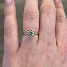 a person's hand with a ring on it and a diamond in the middle