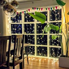 a dining room table with chairs and lights on the window sill in front of it