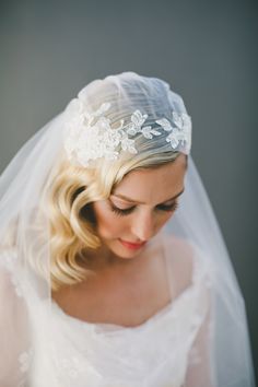 a woman wearing a veil with flowers on the head and hair comb in her hand