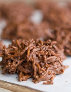 some chocolate cookies are sitting on a piece of parchment paper and ready to be eaten