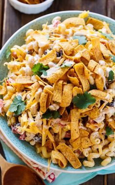 a blue bowl filled with corn salad on top of a wooden table