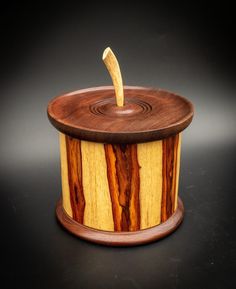 a wooden box with an apple inside on a black tableclothed surface and the lid is made out of wood