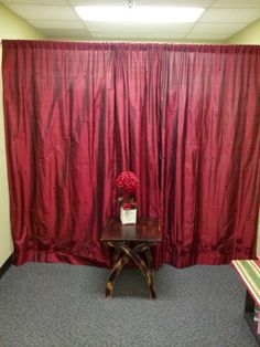 a room with red curtains and a small table