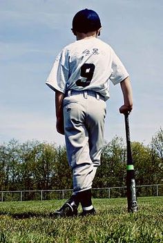 a young boy holding a baseball bat on top of a field