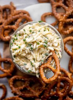 a bowl of food with onion rings on the side next to some pretzels