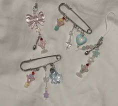 three pairs of earrings with charms attached to them on a white cloth covered tablecloth