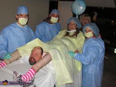 a group of people in scrubs and masks are around a man laying on a hospital bed