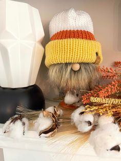 a knitted hat on top of a shelf next to cotton balls and other items