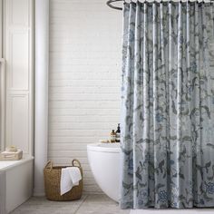 a white bath tub sitting next to a shower curtain with blue flowers on it in a bathroom