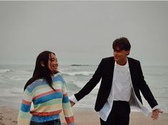 two people walking on the beach holding hands