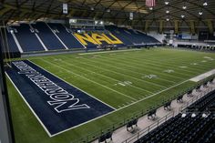 an empty football stadium filled with lots of blue seats and green field covered in yellow letters