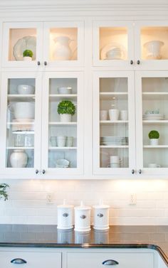 a kitchen with white cabinets and glass front cabinets