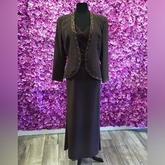 a woman's dress and jacket on display in front of a purple flower wall