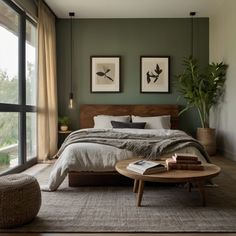 a bedroom with green walls and two pictures on the wall above the bed, along with a round coffee table