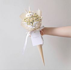 a hand holding a white flower bouquet with yellow and white sprinkles on it