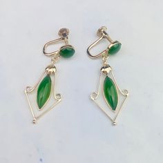 "These beautiful vintage mid-century drop earrings are acquired from an estate auction. The 18K yellow gold heavy earrings feature one round cabochon and one marquise cabochon jade set in bezel setting on each earring and a dangling gold floral frame around the marquise stone. Screw backs tighten securely.  The earrings are 35.6mm (1.40\") long and 14.2mm (0.56\") wide at its widest point, they weigh 3.943 grams. They are marked 18K, and CKP and KPT on the back of the screws, C on one and T on t Art Deco Oval Earrings For Formal Occasions, Oval Art Deco Earrings For Formal Occasions, Formal Oval Art Deco Earrings, Retro Yellow Gold Formal Earrings, Mid-century Polished Formal Jewelry, Vintage Formal Clip-on Earrings With Polished Finish, Classic Green Clip-on Earrings For Formal Occasions, Yellow Gold Marquise Earrings For Formal Occasions, Classic Green Clip-on Earrings