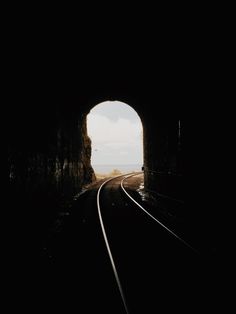 the light at the end of the tunnel is shining on the train tracks that lead into the distance