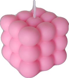 a pink candle that is on top of a white surface with some balls around it